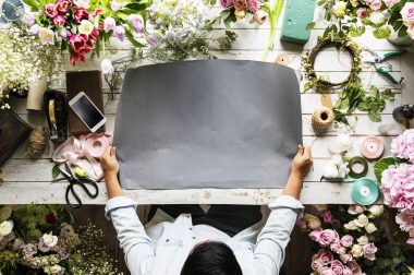 Florist Showing Empty Design Space Paper on Wooden Table with Fresh Flowers Decorate